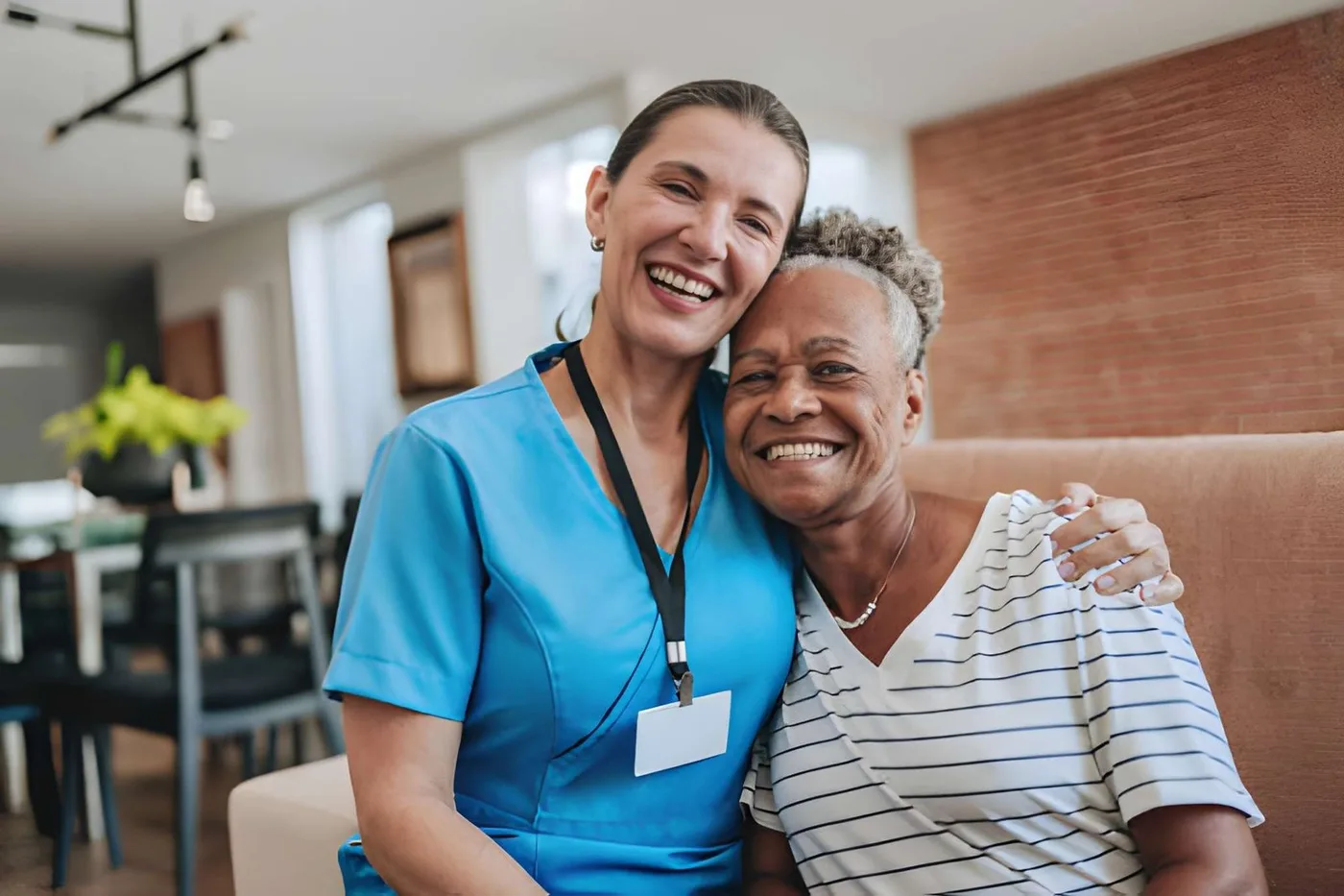 A care professional and older adult smiling together at home