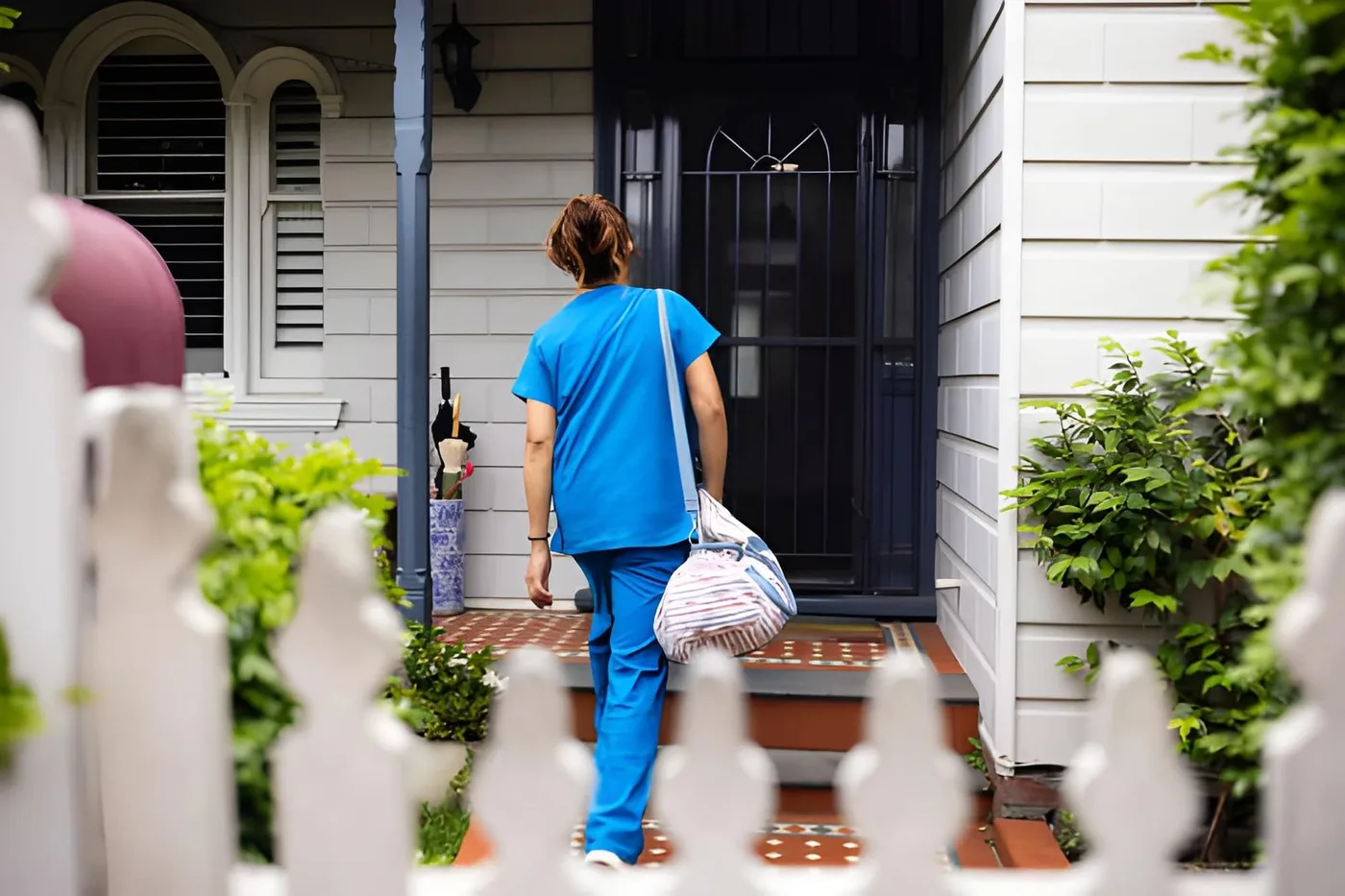 A home care professional arriving at the front door of a house