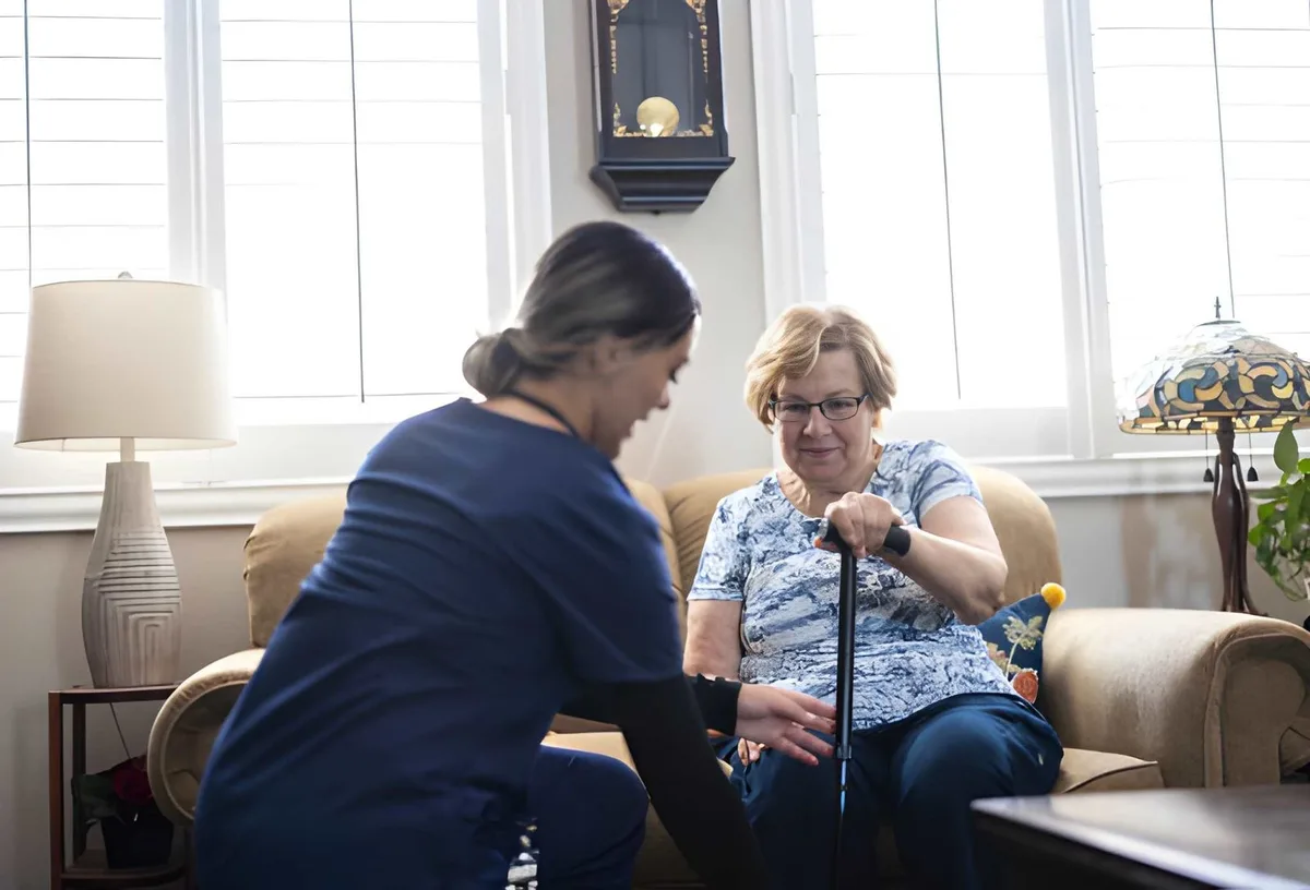 A care professional helping an older adult adjust a walking cane at home